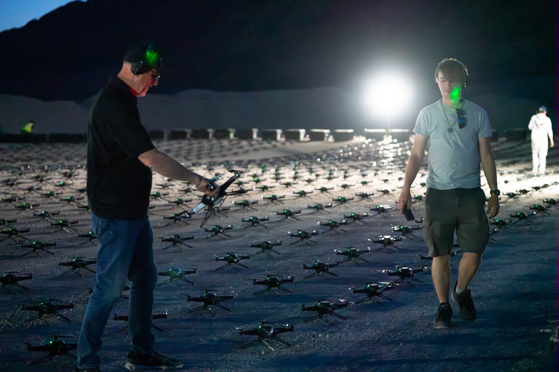 Crew members wearing headsets preparing drones arranged in rows before The Boys show